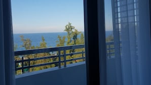 Ein Balkon mit Blick auf das Meer und Bäume.