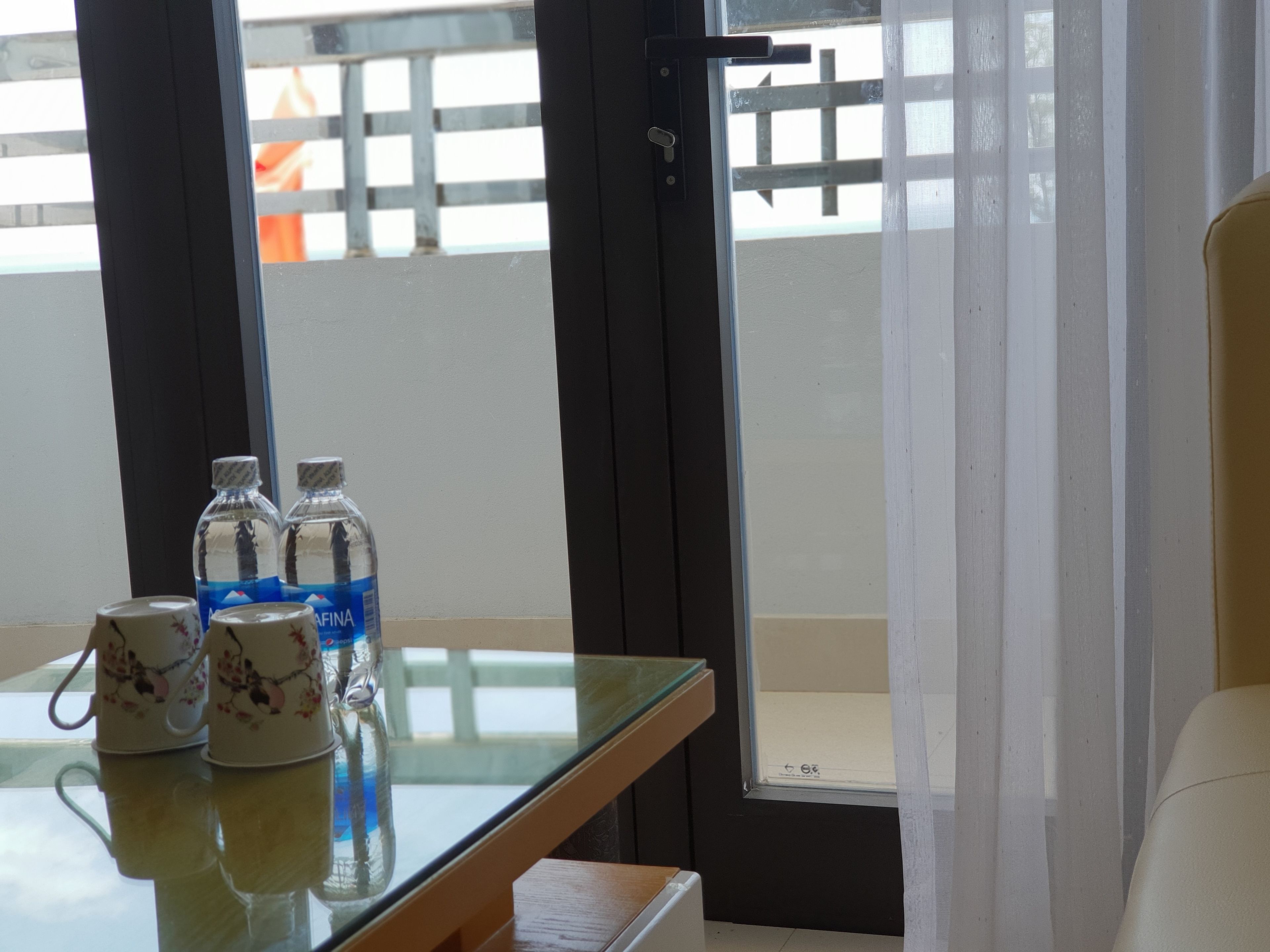 A room with a glass table, two water bottles, and two cups with floral designs.