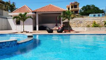 Una piscina al aire libre, sillones reclinables de piscina