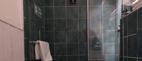 Un baño moderno con ducha envuelta en vidrio, un inodoro blanco y un perchero para toallas.