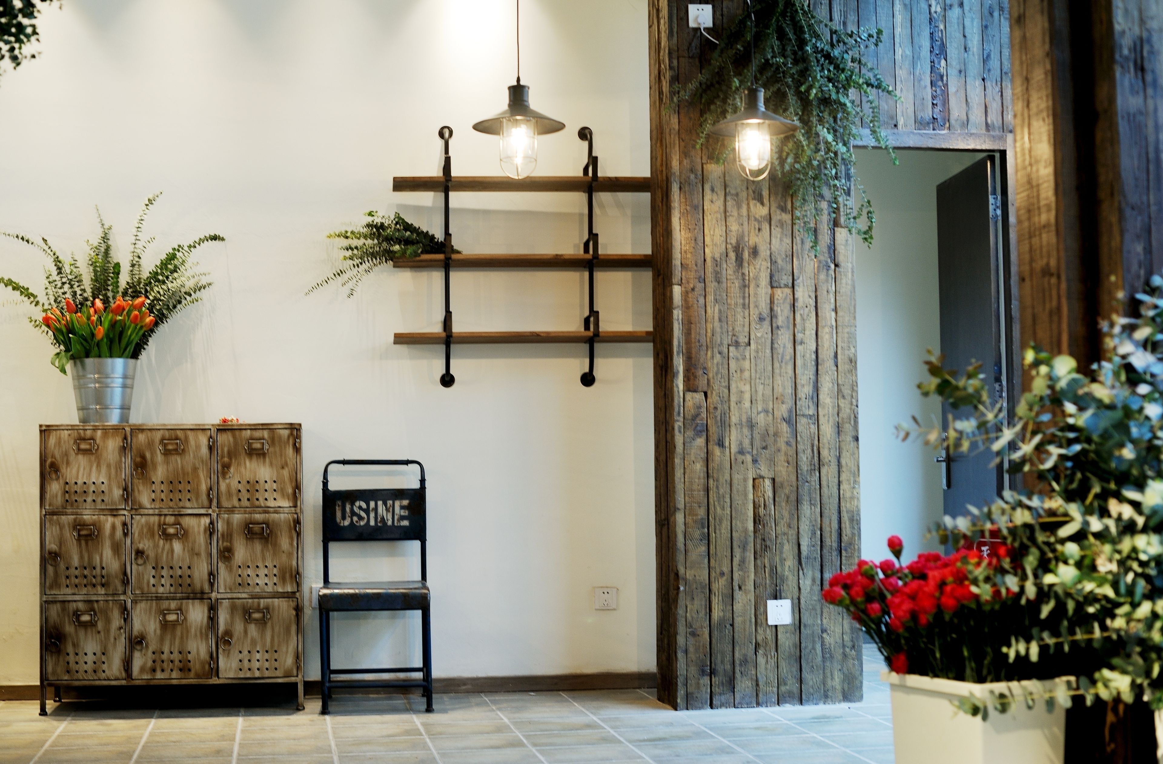 Una habitación con un aparador de madera, un banco, una estantería mural con plantas y una lámpara colgante.