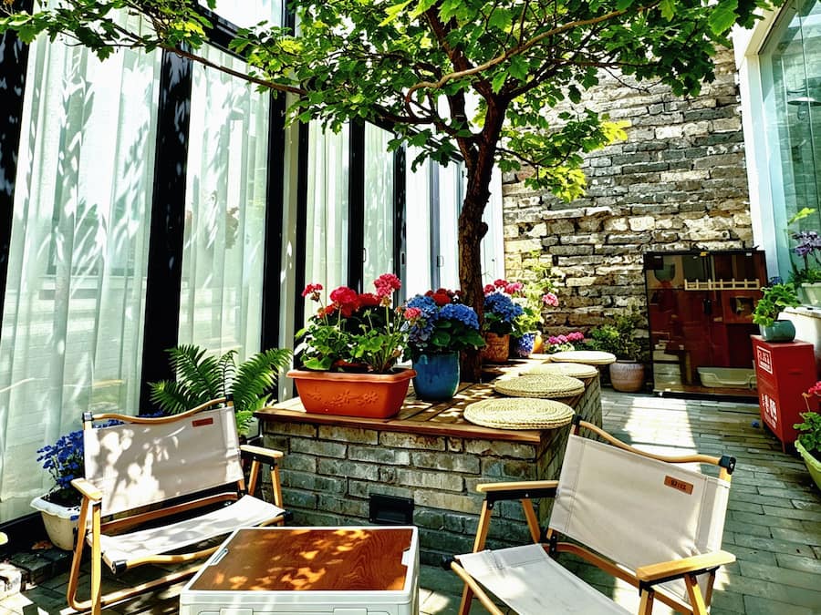 Un patio al aire libre con paredes de piedra, plantas en macetas y asientos.