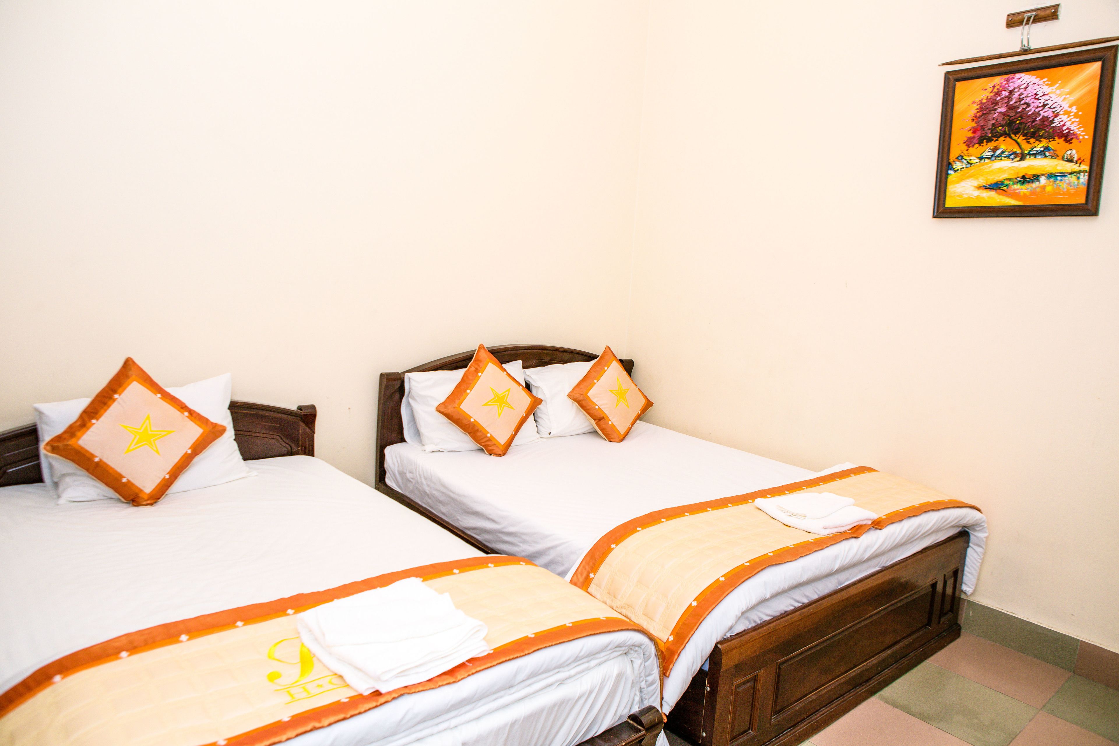 Two single beds with matching headboards, white bedding, and orange accents.