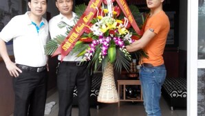 Three people standing in a doorway with a large floral arrangement. - Star Hotel Hai Duong (Hai Phong)