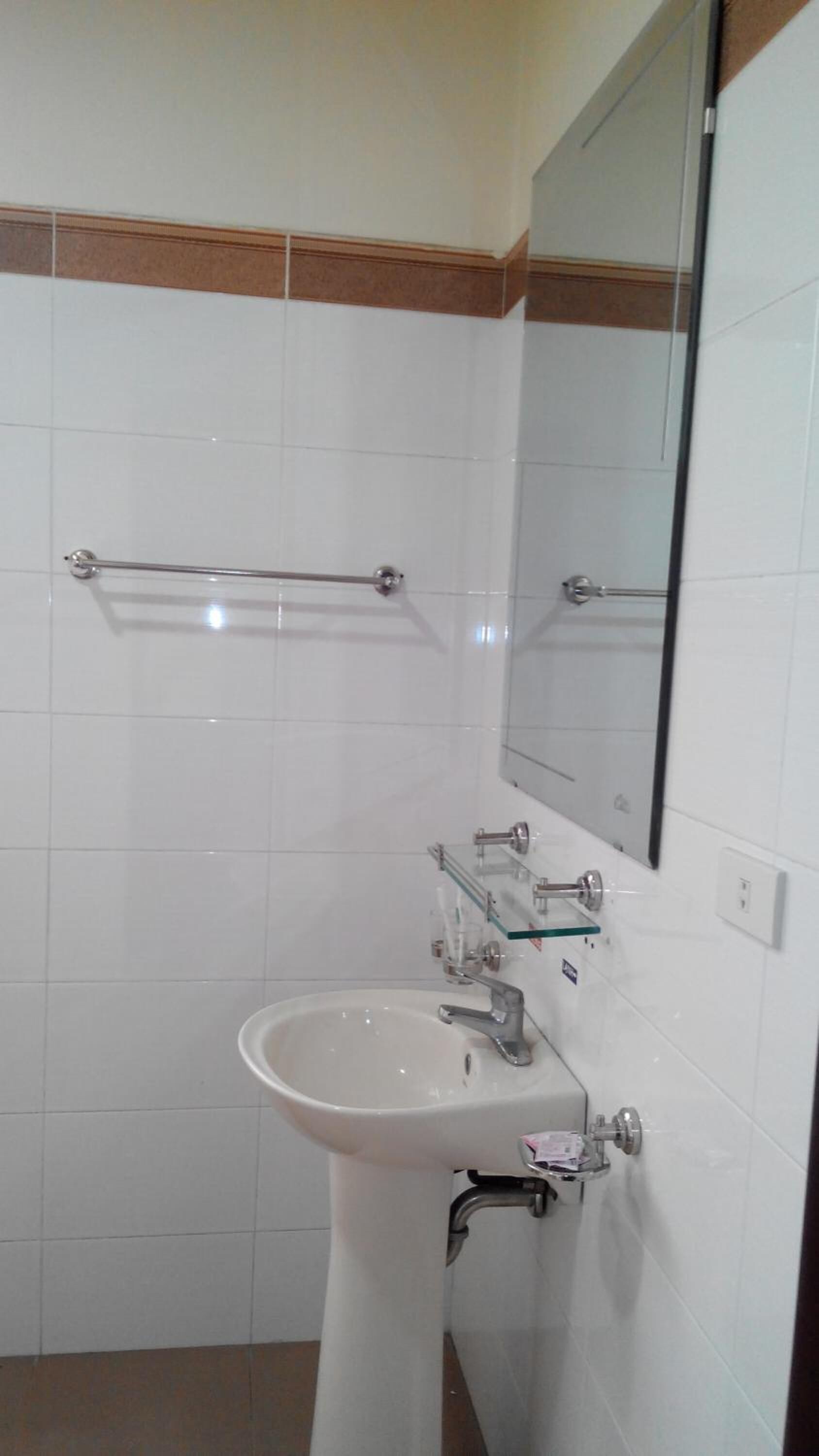 A bathroom with a white sink, a mirror, and a towel rack.