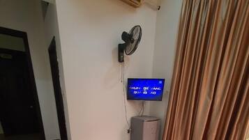 Habitació d'hotel amb un llit, una televisió, aire condicionat i una cortina.