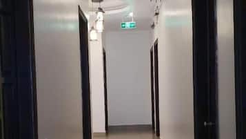 A corridor with doors on both sides, a ceiling light, and a visible exit sign.
