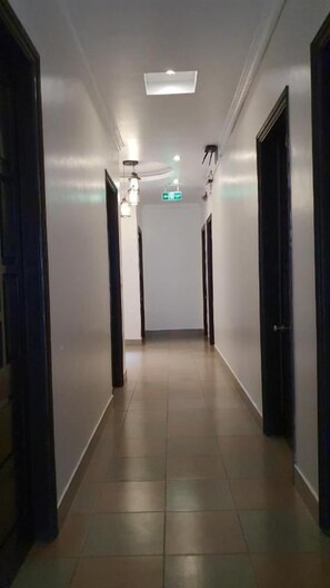 Un pasillo con puertas a ambos lados, una luz en el techo y una señal de salida visible.