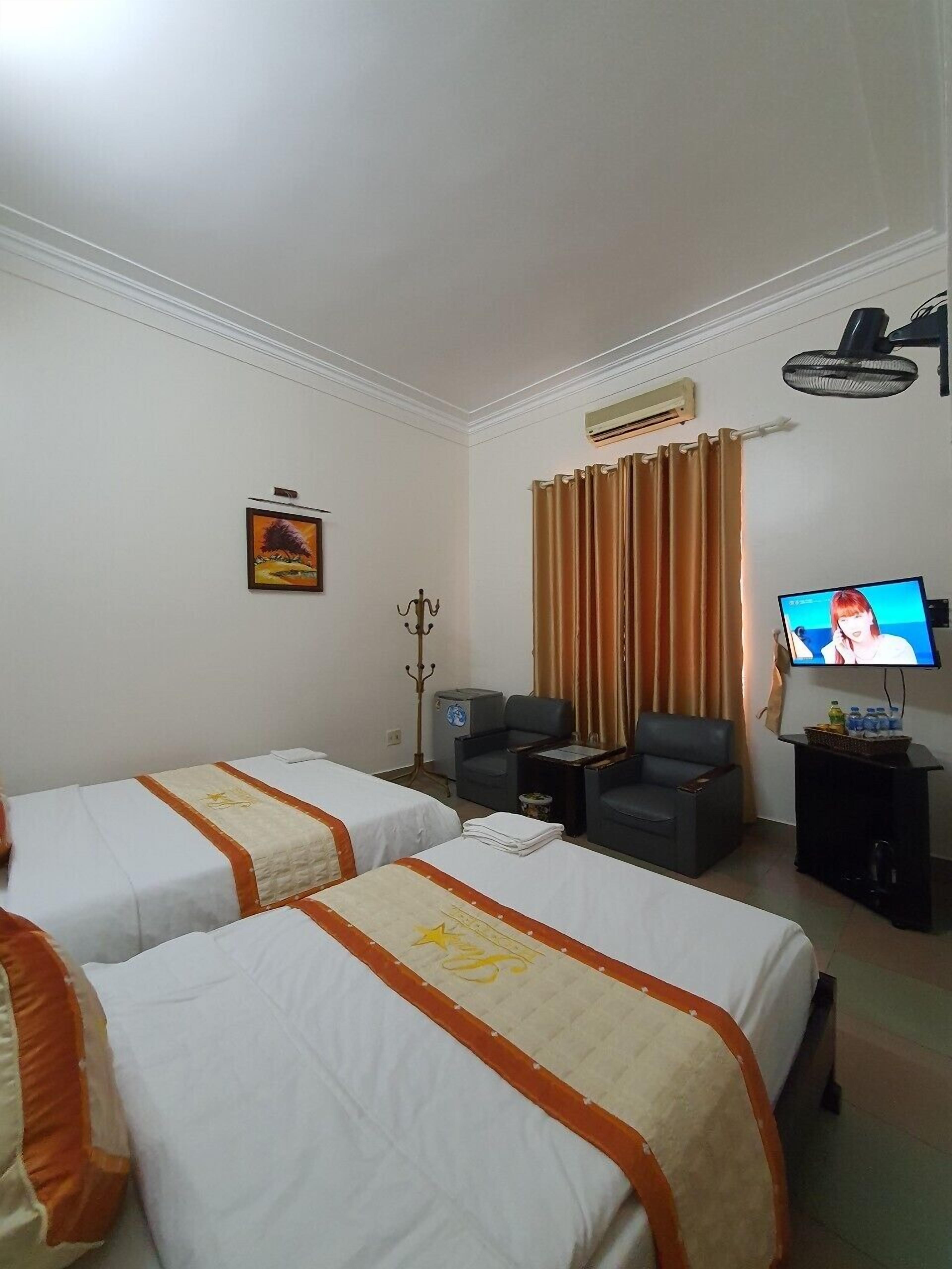 A hotel room with two beds, a television, a desk, and a chair.