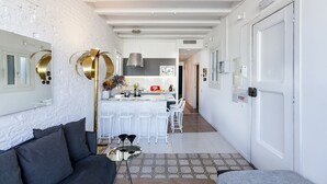 Una cocina moderna con armarios blancos, una isla central y taburetes blancos.