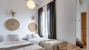 Un dormitorio con dos camas, un espejo grande y dos adornos tejidos en la pared.