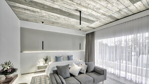 A modern living room with a grey sofa, a patterned rug, and a large window with sheer curtains. - Chan Boutique (Sihanoukville)