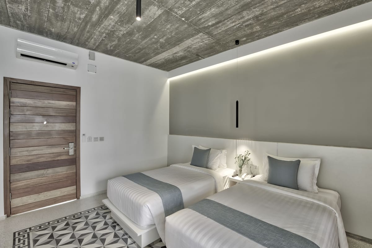 Un dormitorio moderno con dos camas, una puerta de madera y un tapete con estampado geométrico.