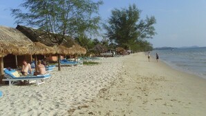 A beach with sun loungers and thatched-roof huts along the shoreline. - Chan Boutique (Sihanoukville)