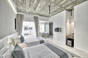 A modern bedroom with two beds, a large window, a stone accent wall, and a flat-screen TV. - Chan Boutique (Sihanoukville)