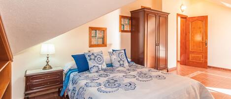 A bedroom with a bed, a nightstand, a wardrobe, and a door.