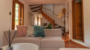 Een woonkamer met een bank, een bijzettafeltje en een trap.