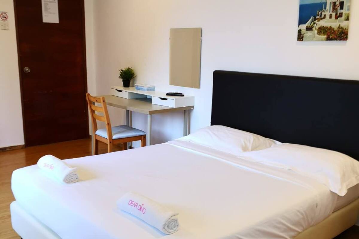 A hotel room with a bed, a desk, a chair, and a painting on the wall.