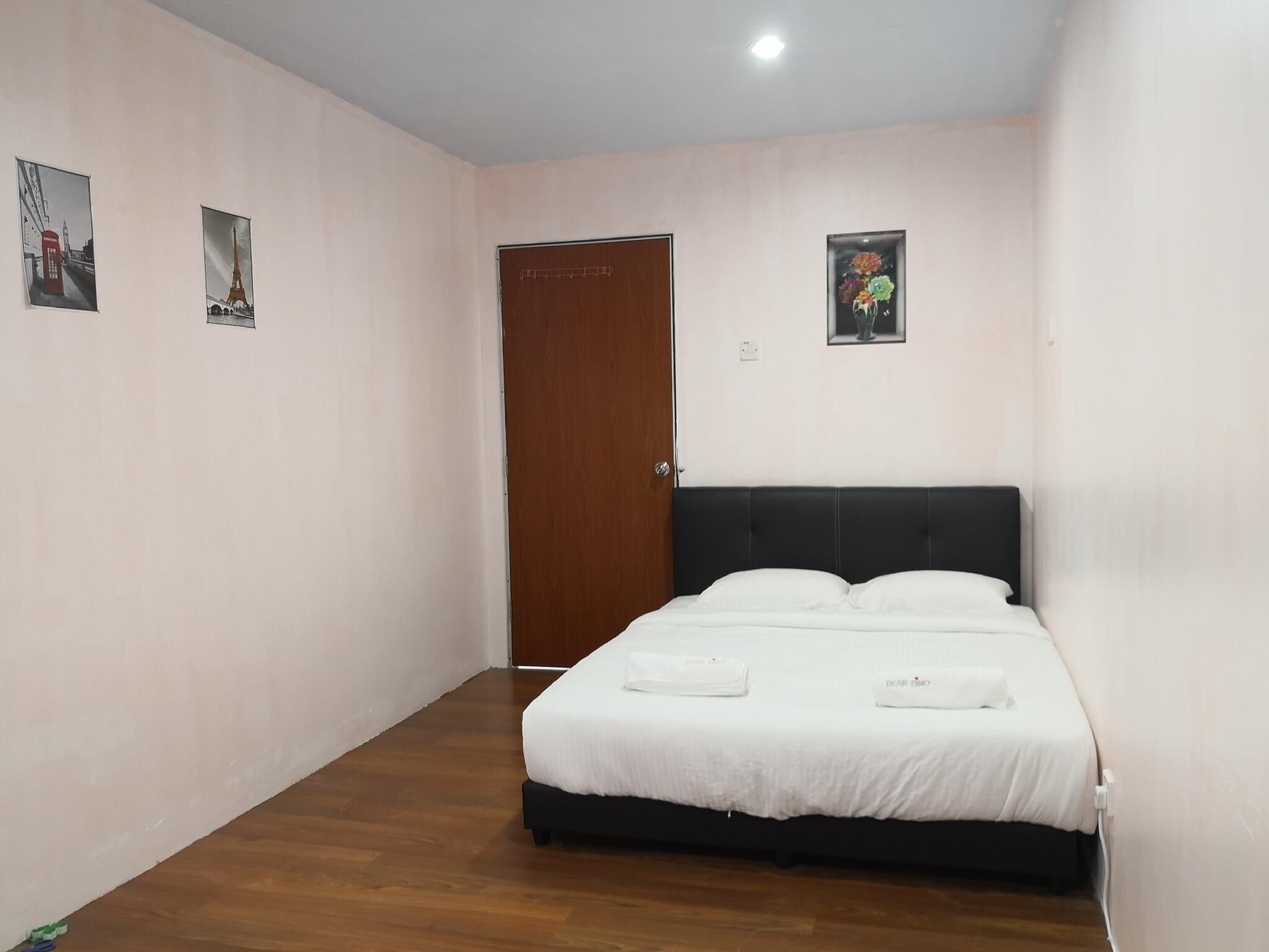 Un dormitorio con una cama, una puerta de madera y dos cuadros en la pared.