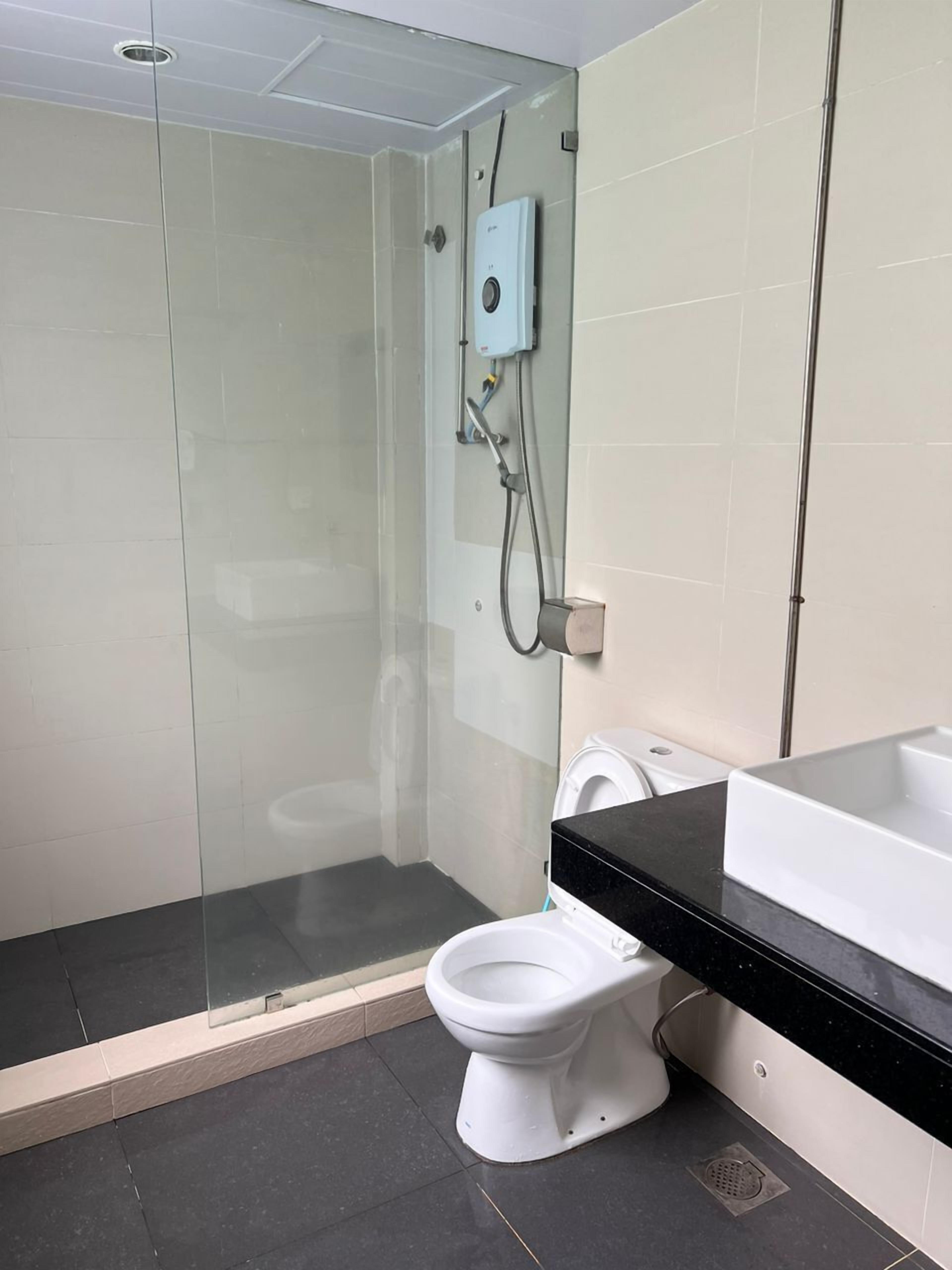 Un bagno moderno con cabina doccia in vetro, un water bianco e un piano di appoggio nero.