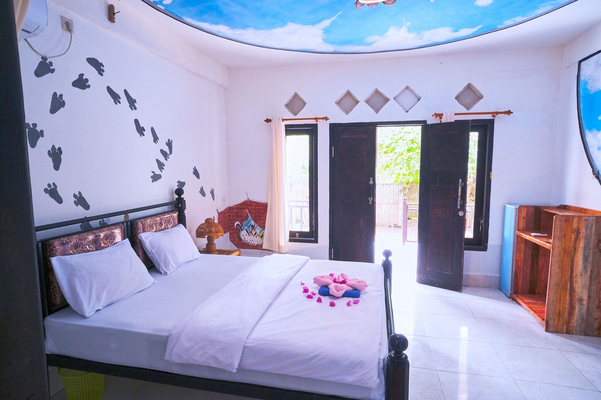 A bedroom with a bed, a wooden cabinet, and a door leading outside.