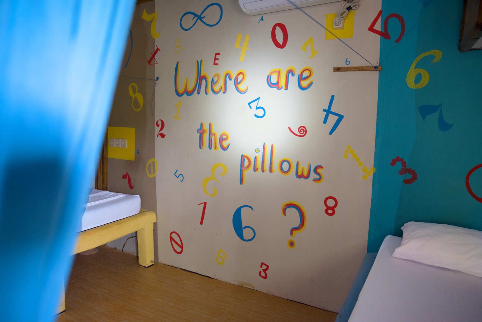 Habitación infantil con un muro decorado con números y el texto '¿Dónde están los almohadones?'