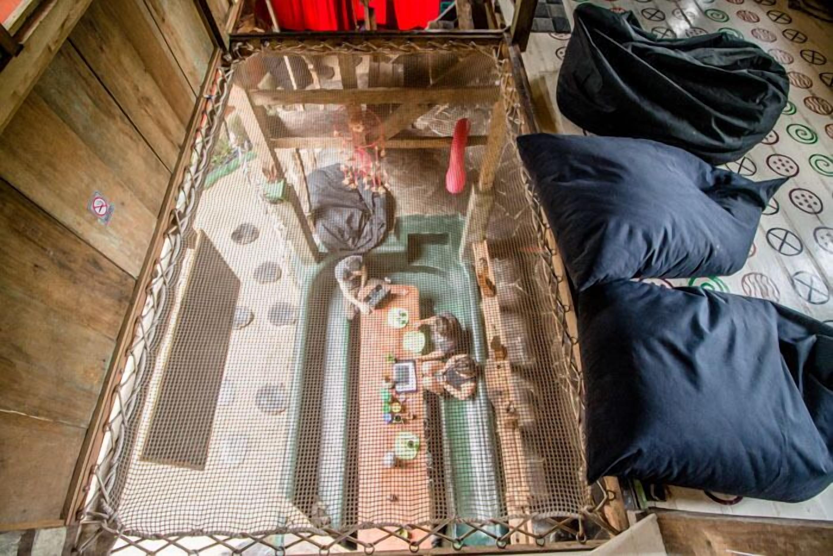 Una habitación con una cama, un mosquitero y una bolsa negra en el suelo.