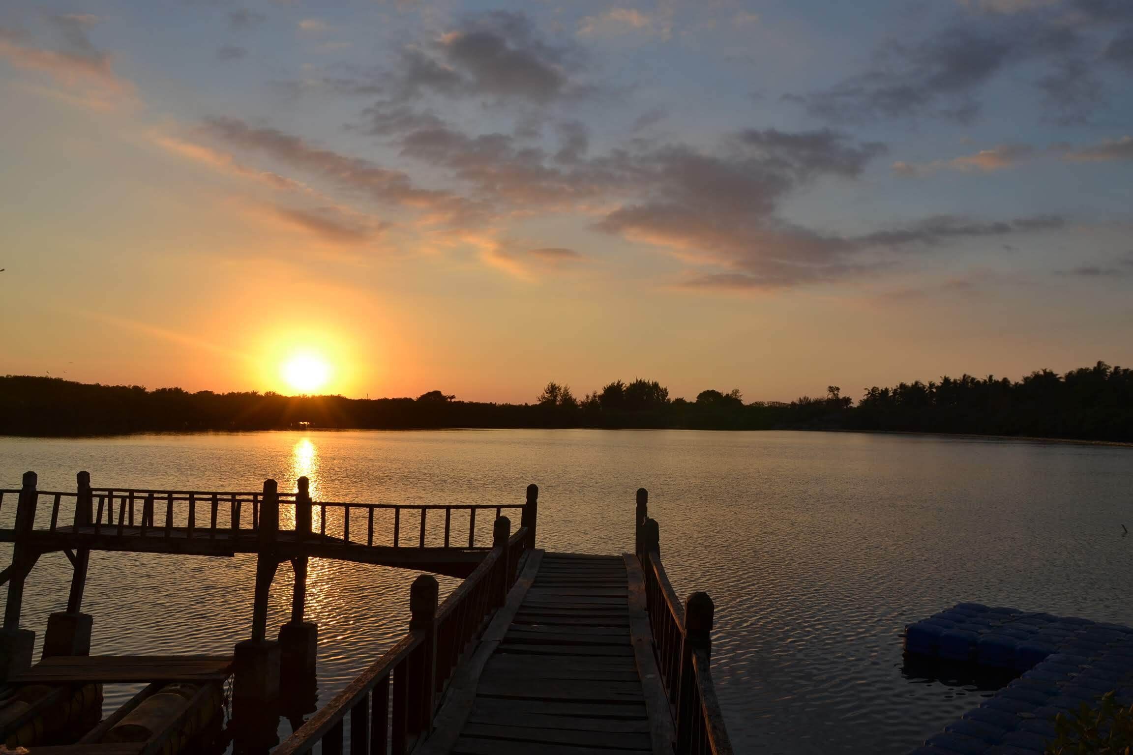 Un muelle de madera que se adentra en un lago tranquilo al atardecer.