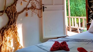 A bedroom with a bed, a door, and a view of greenery outside. - The Rabbit Tree - Hostel (Gili Meno)