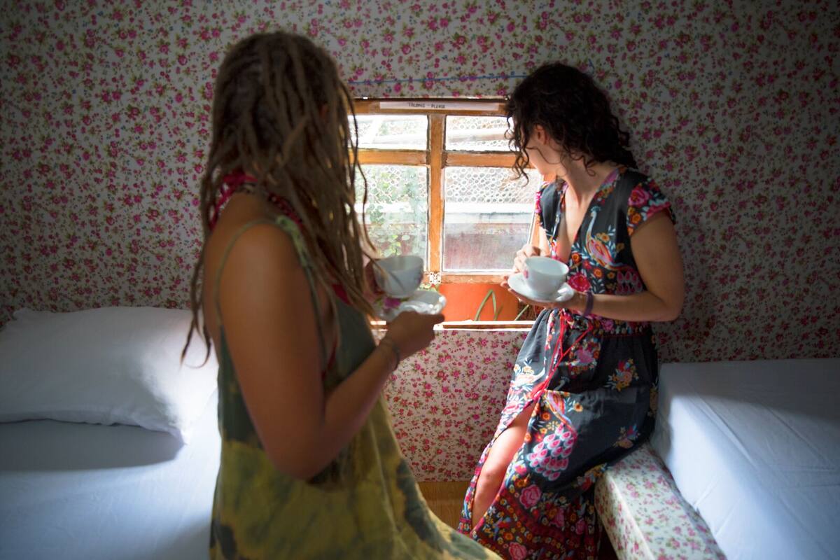 Ein Zimmer mit blumigem Wandpapier, einem Fenster und einem Bett.