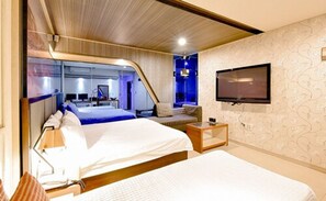 Une chambre moderne avec un grand lit, un canapé, une télévision et un bureau.