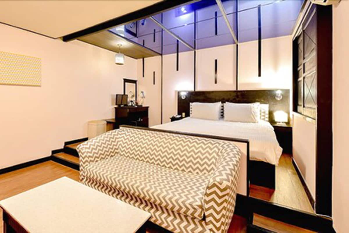 A modern hotel room with a large bed, a sofa, and a desk.