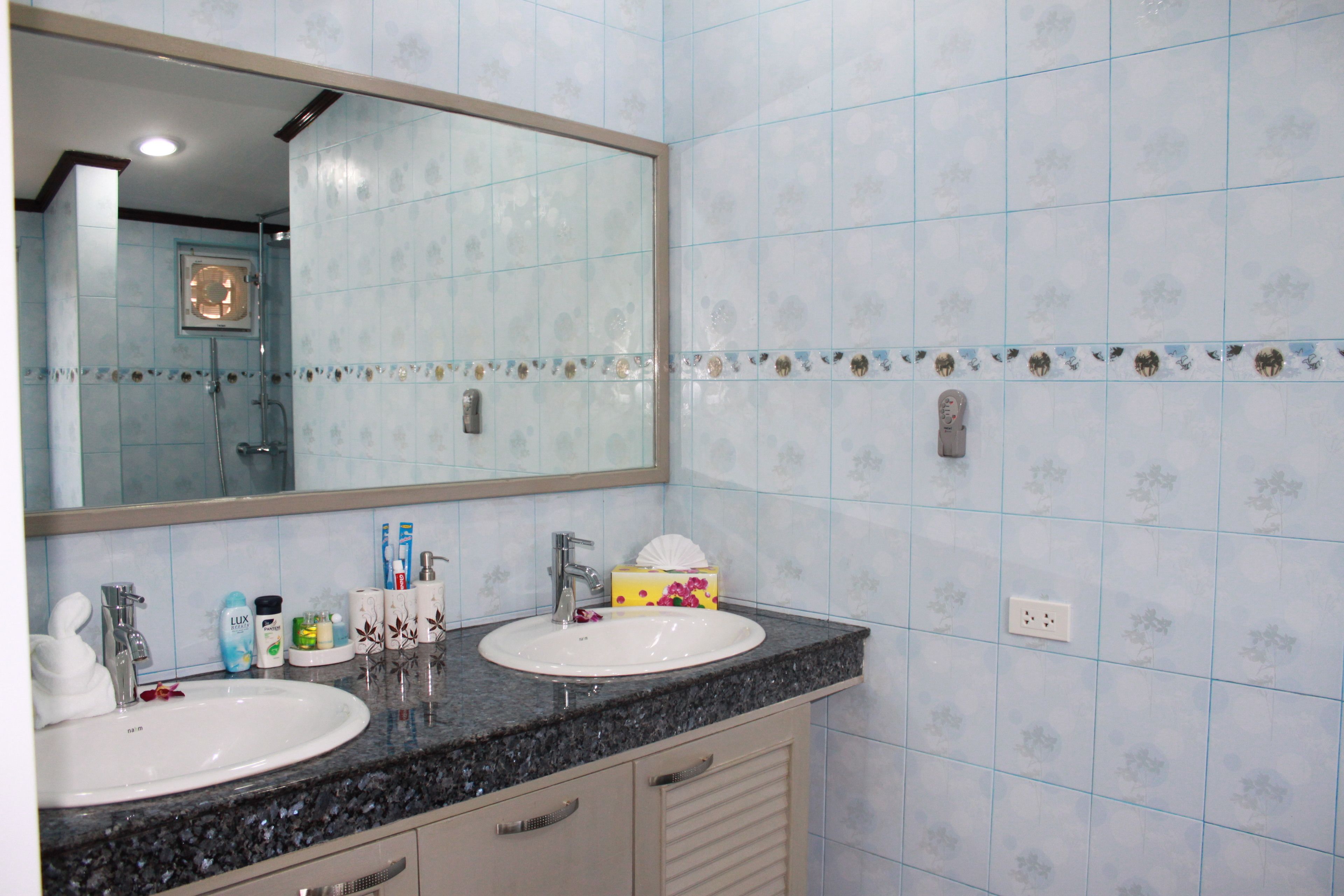 A bathroom with two sinks, a large mirror, and a tiled wall.