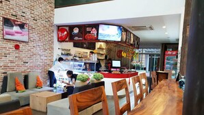 Un cafè amb paret de maó, mostrador amb carta i zones d'aixecament.