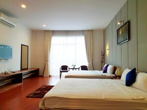 A hotel room with two beds, a desk with a chair, a TV, and a large window with curtains. - D.I Residence Boutique Hotel (Phnom Penh)