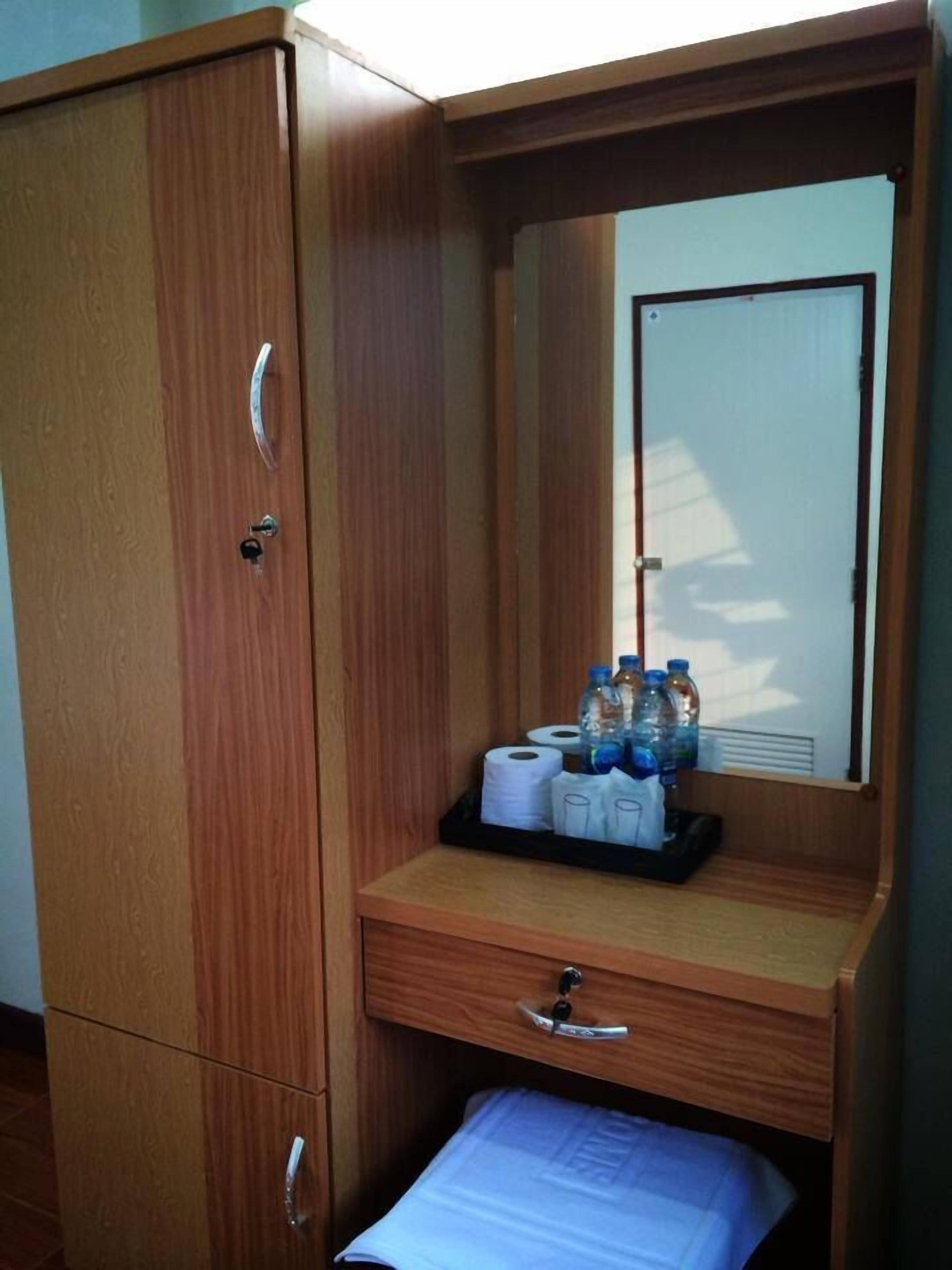 A wooden wardrobe with a mirror, a small drawer, and a shelf with toiletries.