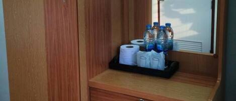 A wooden wardrobe with a mirror, a small drawer, and a shelf with toiletries.