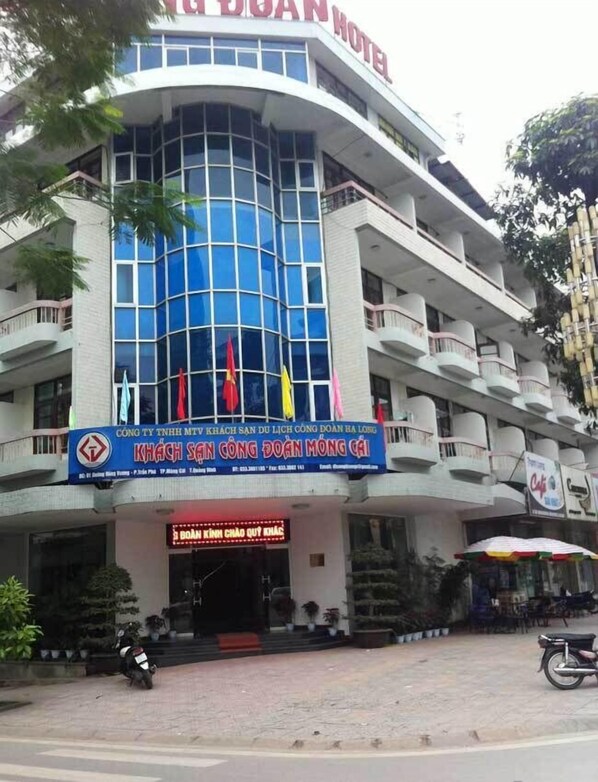 A hotel with a curved facade, multiple balconies, and flags.