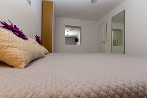 Um quarto com cama, porta e espelho.