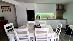 A compact kitchen with white cabinetry, a built-in oven, and a stainless steel range hood.