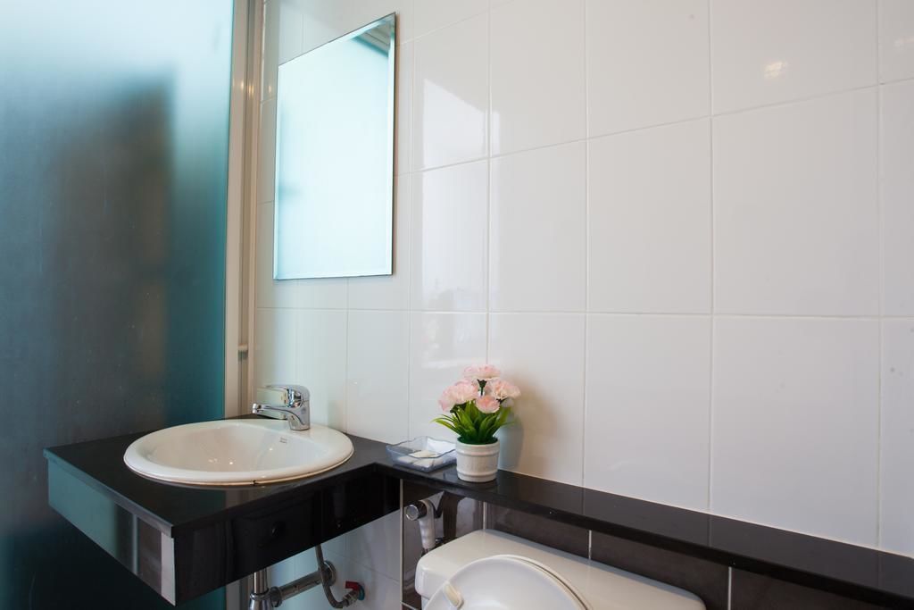 A modern bathroom with a white sink, black countertop, and a mirror above it.