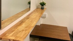 Una esquina con un estante de madera, una mesita, un enchufe y dos plantas en macetas.