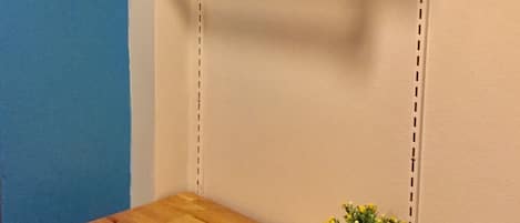 Une étagère d’angle avec une tablette supérieure en bois et une plante en pot sur l’étagère inférieure.