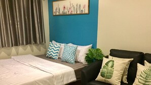 Un dormitorio con una cama, un sofá negro y un cuadro en la pared.