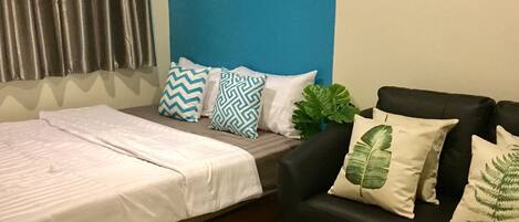 A bedroom with a bed, a black sofa, and a painting on the wall.