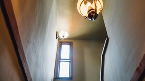 Una escalera con una araña y un ventanal en la parte superior.