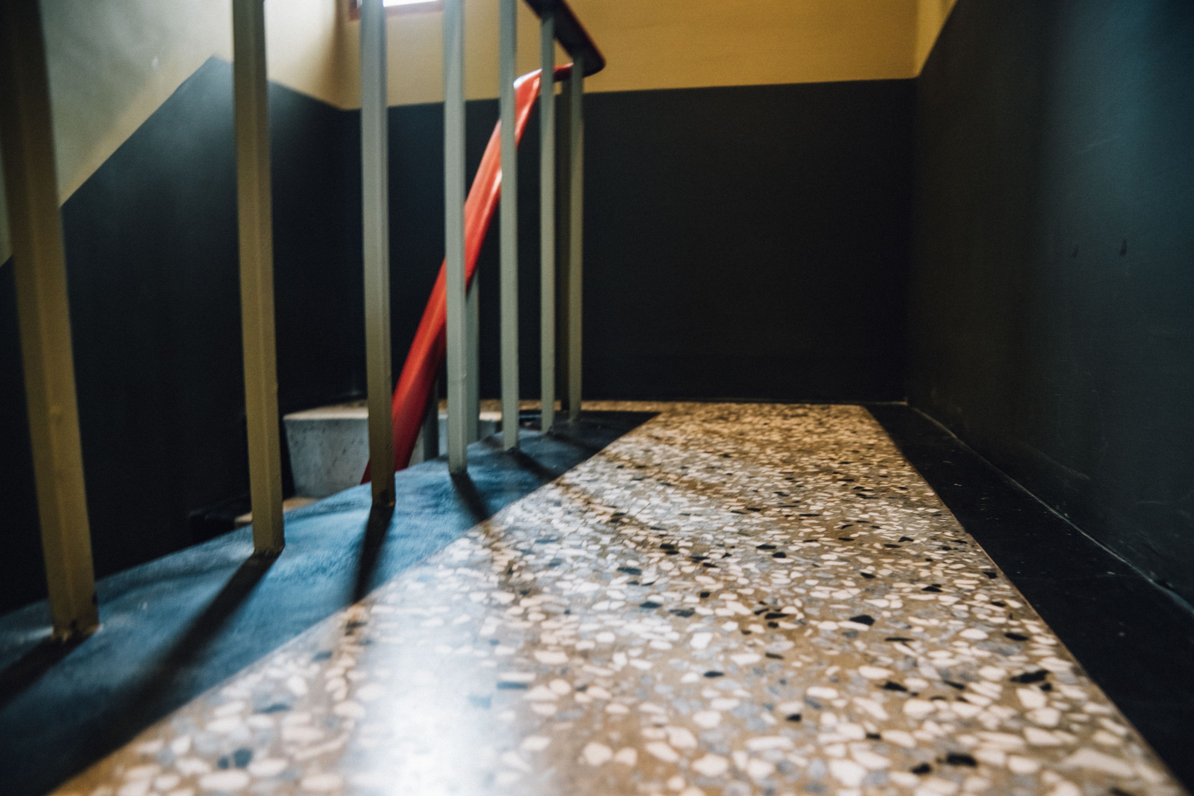 A staircase with a terrazzo floor and metal railings.