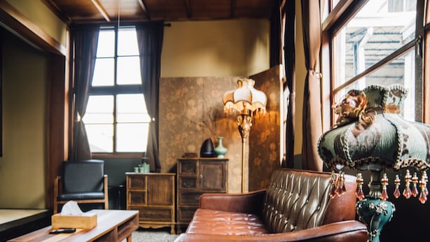 Una habitación con un sofá de cuero marrón, una mesa de centro de madera, una lámpara y una silla.