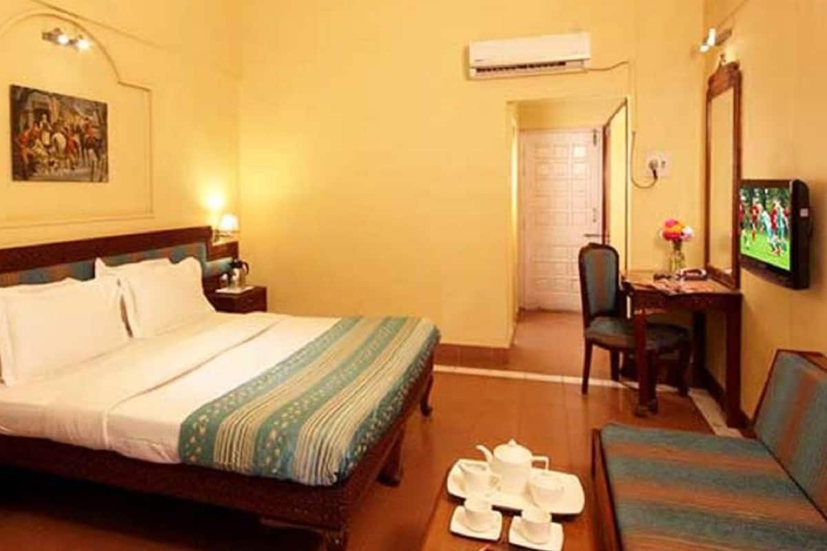 Une chambre d’hôtel équipée d’un lit, d’un bureau avec une chaise, d’une télévision et d’un appareil de climatisation.