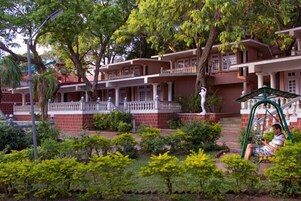 A traditional building with multiple balconies, surrounded by well-maintained greenery and a swing set.